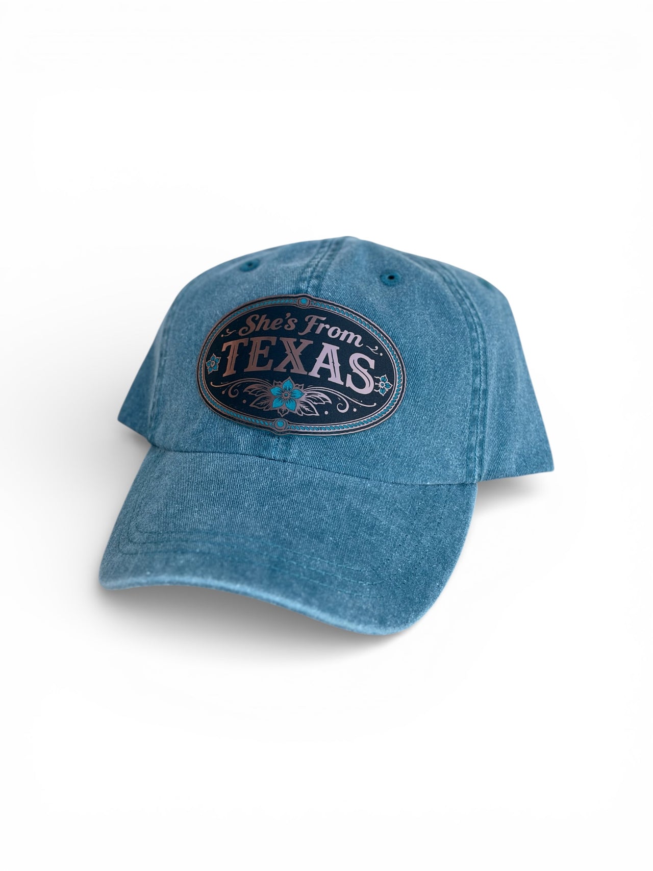 Blue denim cap with 'She's From Texas' text on a white background