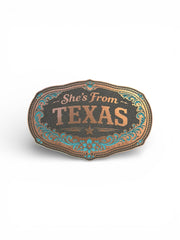 Belt buckle with 'She's From Texas' text on a white background